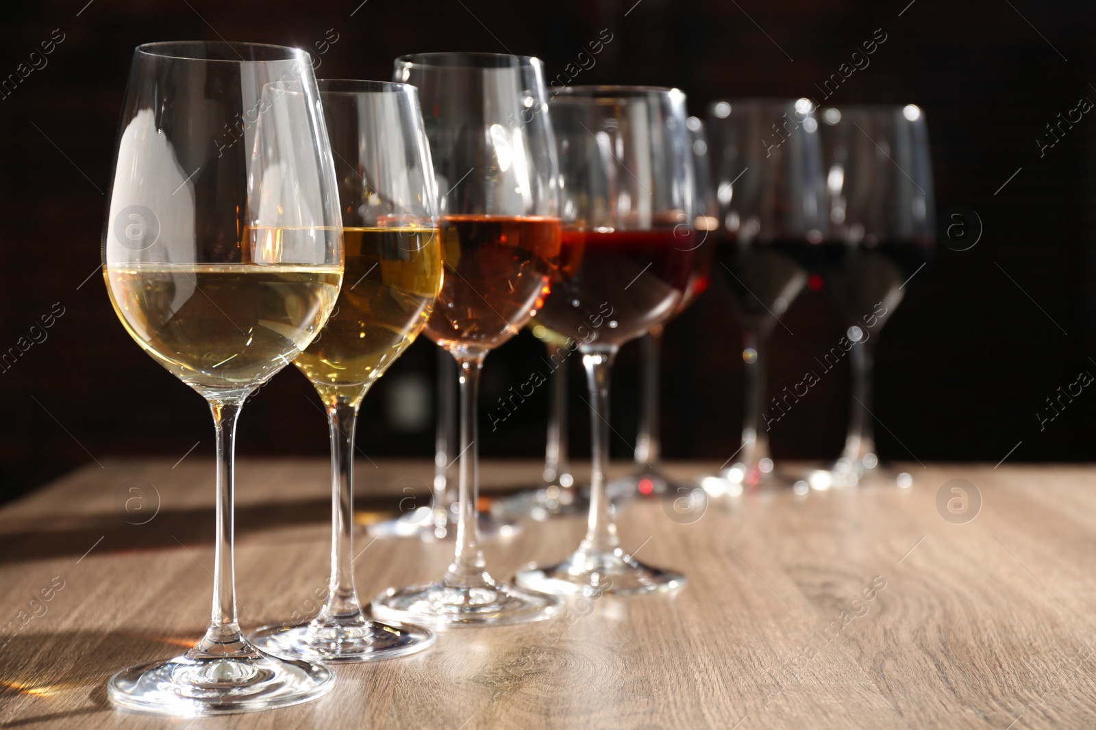 Photo of Different tasty wines in glasses on wooden table, space for text