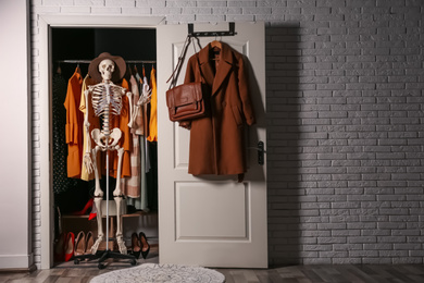 Photo of Artificial human skeleton model in wardrobe room, space for text