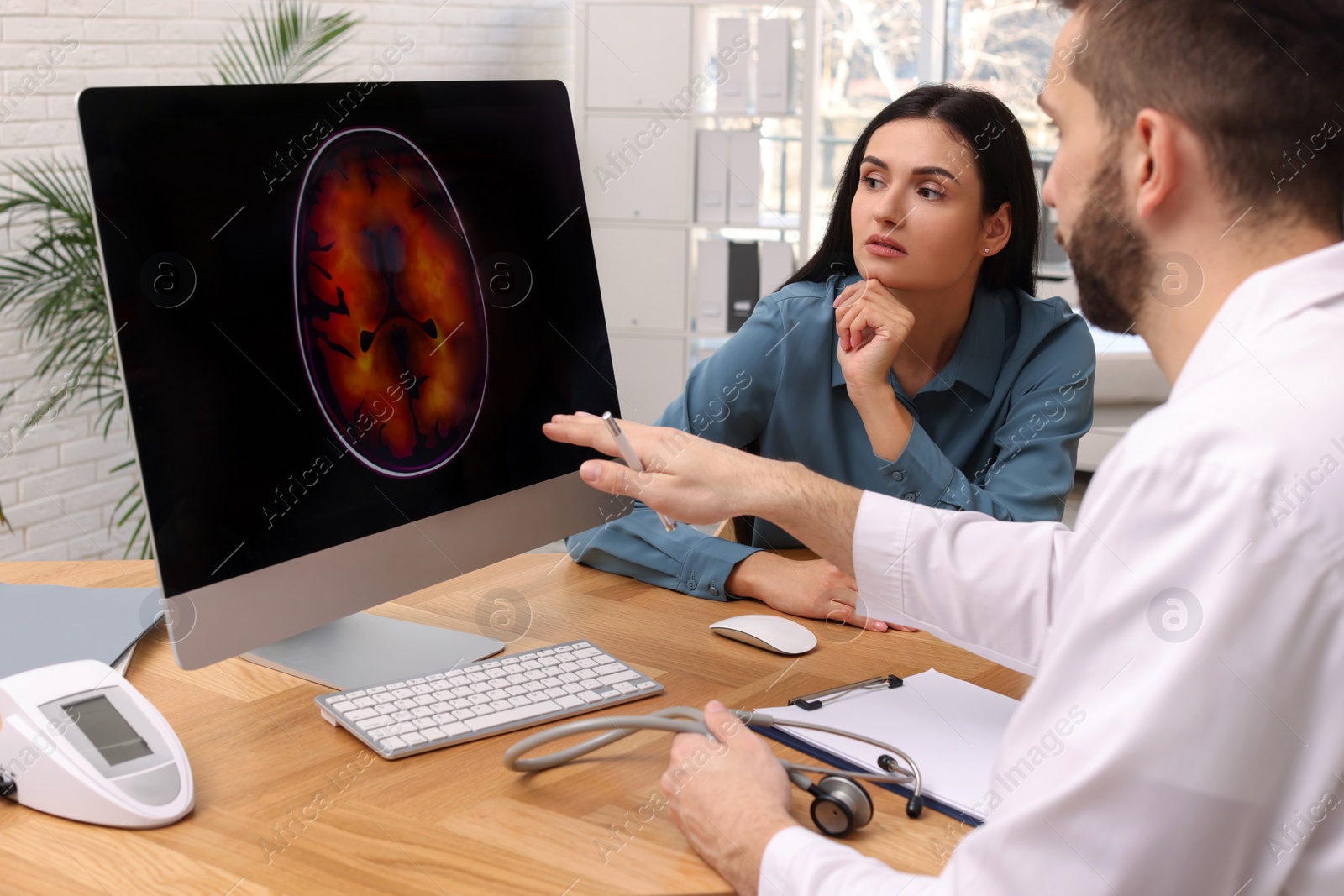 Photo of Neurologist showing brain scan to young woman in clinic