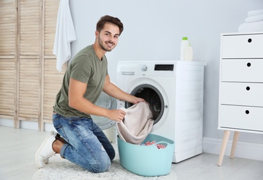 Photo of Young man using washing machine at home. Laundry day