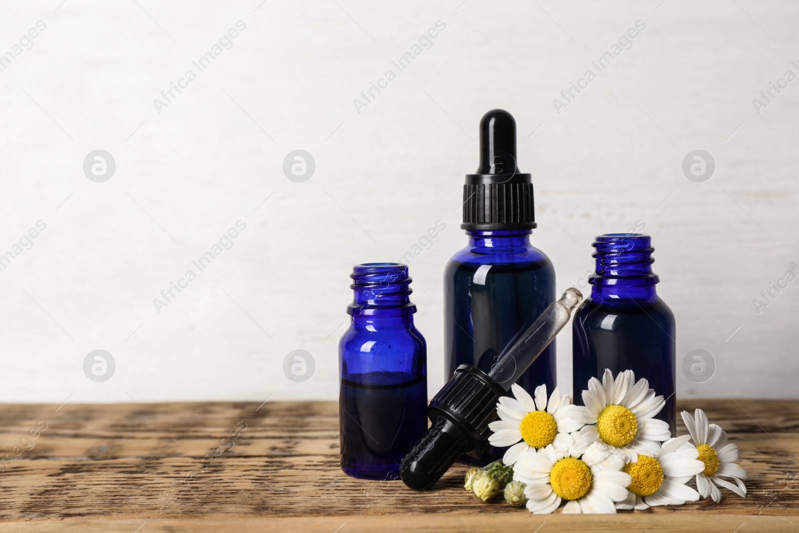 Photo of Composition with bottles of chamomile essential oil on table. Space for text