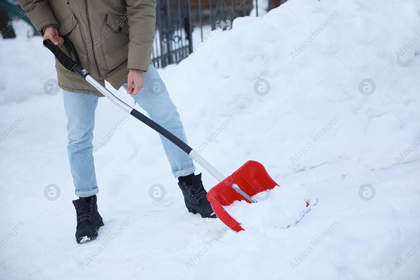 Photo of Man cleaning snow with shovel outdoors on winter day, closeup