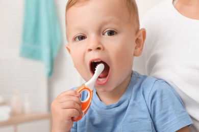 Woman and her son with toothbrush on blurred background