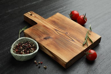 Photo of Wooden cutting board, fresh tomatoes and different spices on grey textured table