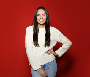 Pretty woman wearing warm sweater on red background 