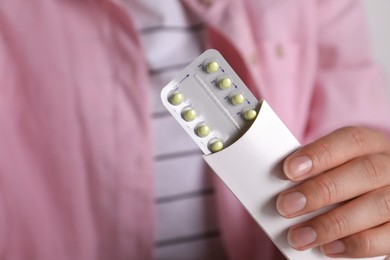 Photo of Woman holding blister of oral contraceptive pills, closeup