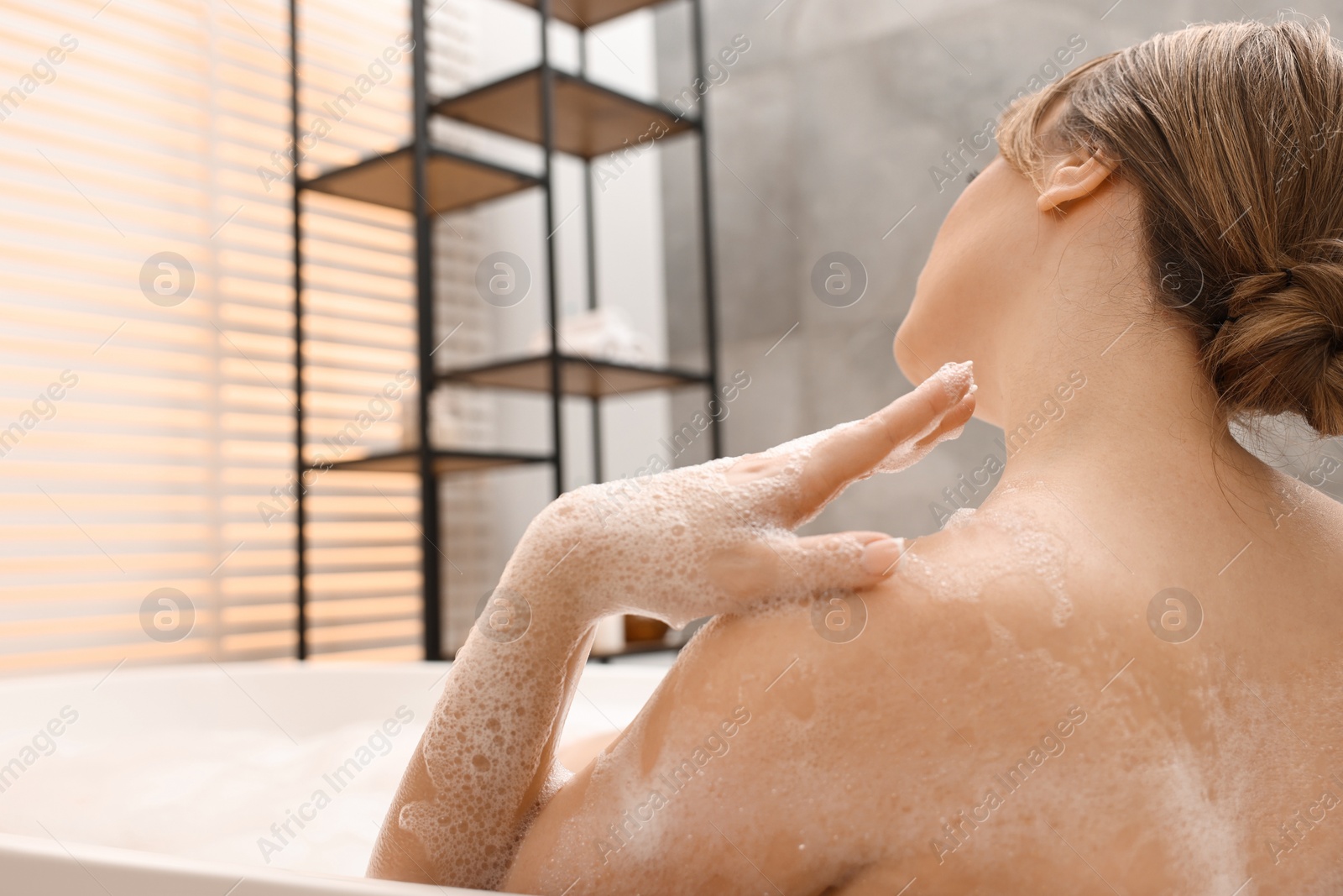 Photo of Woman taking bath with foam in tub indoors. Space for text