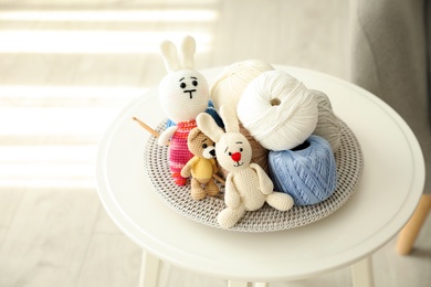 Photo of Crocheted toys and clews on white table. Engaging in hobby