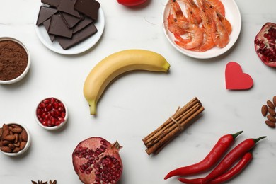 Photo of Natural aphrodisiac. Different food products and red decorative heart on white marble table, flat lay