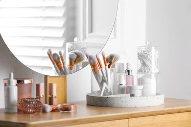 Photo of Containers with cotton swabs and pads near cosmetic products on dressing table