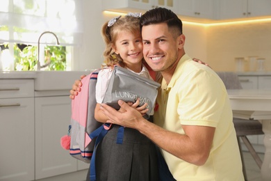 Photo of Father helping his little child get ready for school in kitchen
