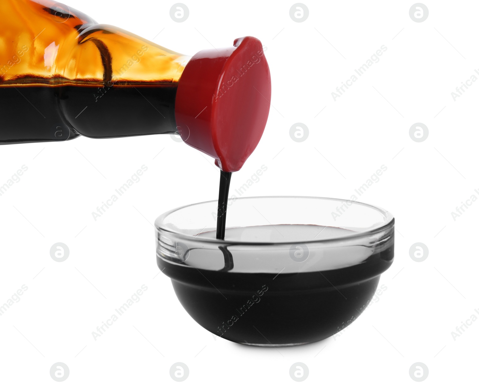 Photo of Pouring soy sauce into bowl against white background