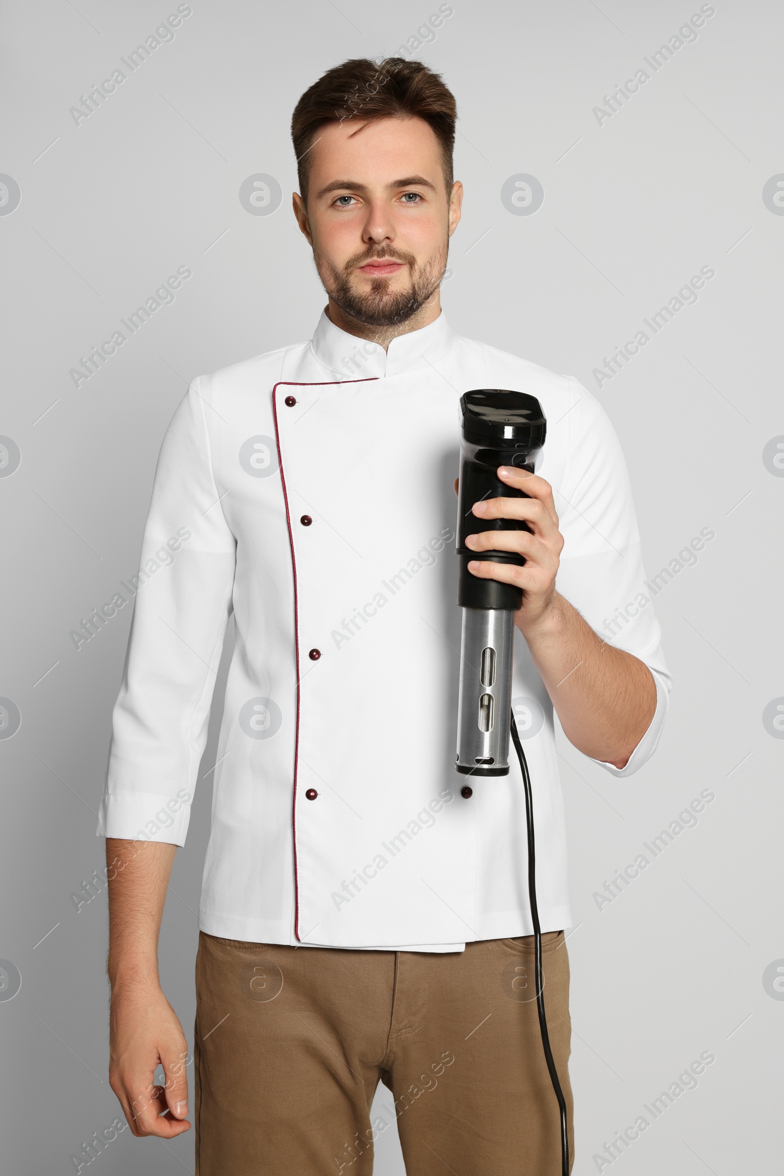 Photo of Chef holding sous vide cooker on beige background