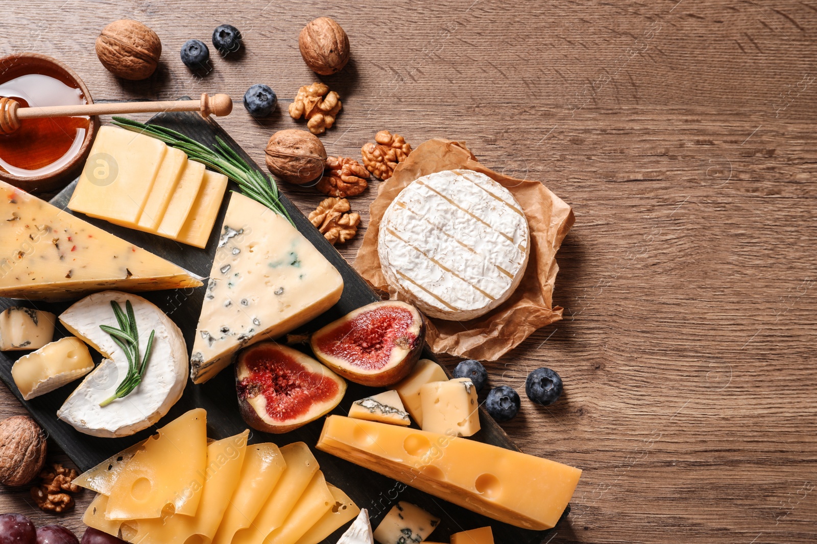 Photo of Different types of delicious cheese served on wooden table, top view. Space for text