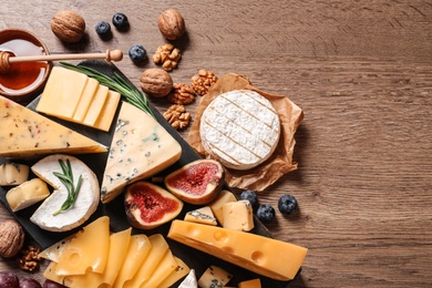 Photo of Different types of delicious cheese served on wooden table, top view. Space for text