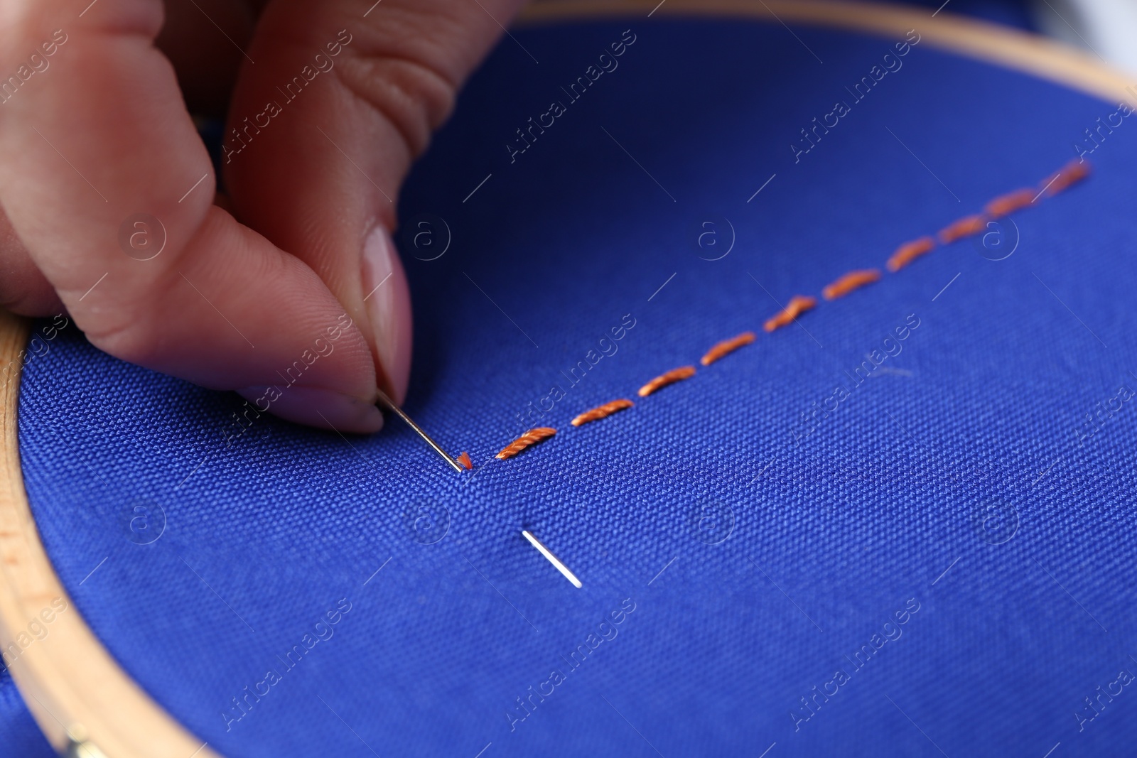 Photo of Woman with sewing needle and thread embroidering on cloth, closeup