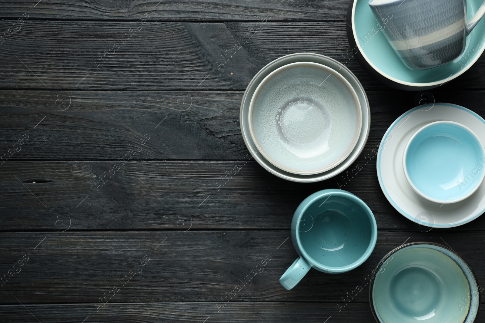 Photo of Stylish empty dishware on black wooden table, flat lay. Space for text