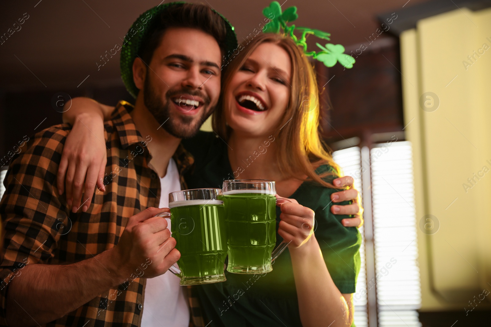 Photo of Young man and woman toasting with green beer in pub. St. Patrick's Day celebration