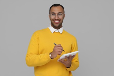 Photo of Happy young intern holding notebook and pen on light grey background