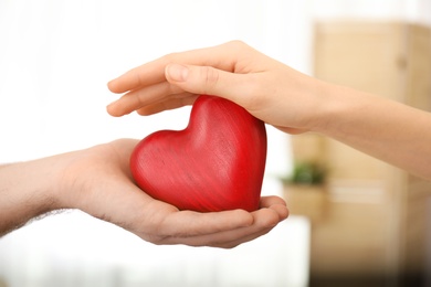 Photo of Couple holding wooden heart on blurred background, closeup