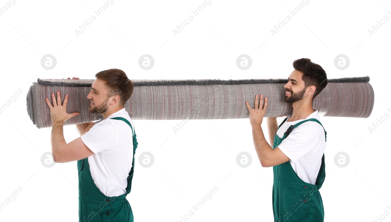 Photo of Young workers carrying rolled carpet isolated on white. Moving service