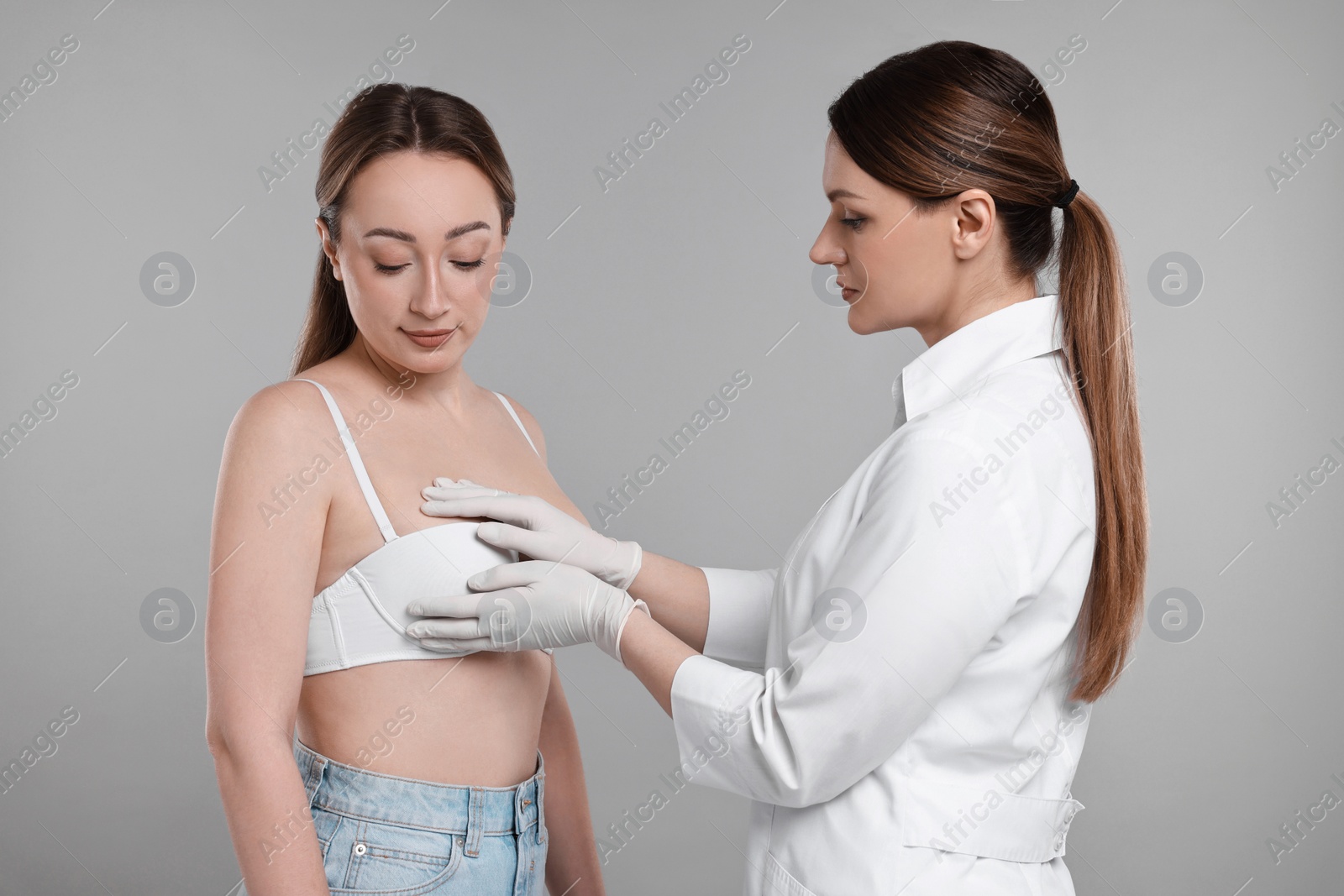 Photo of Mammologist checking woman's breast on gray background