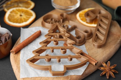 Photo of Different cookie cutters and ingredients on black table. Christmas treat