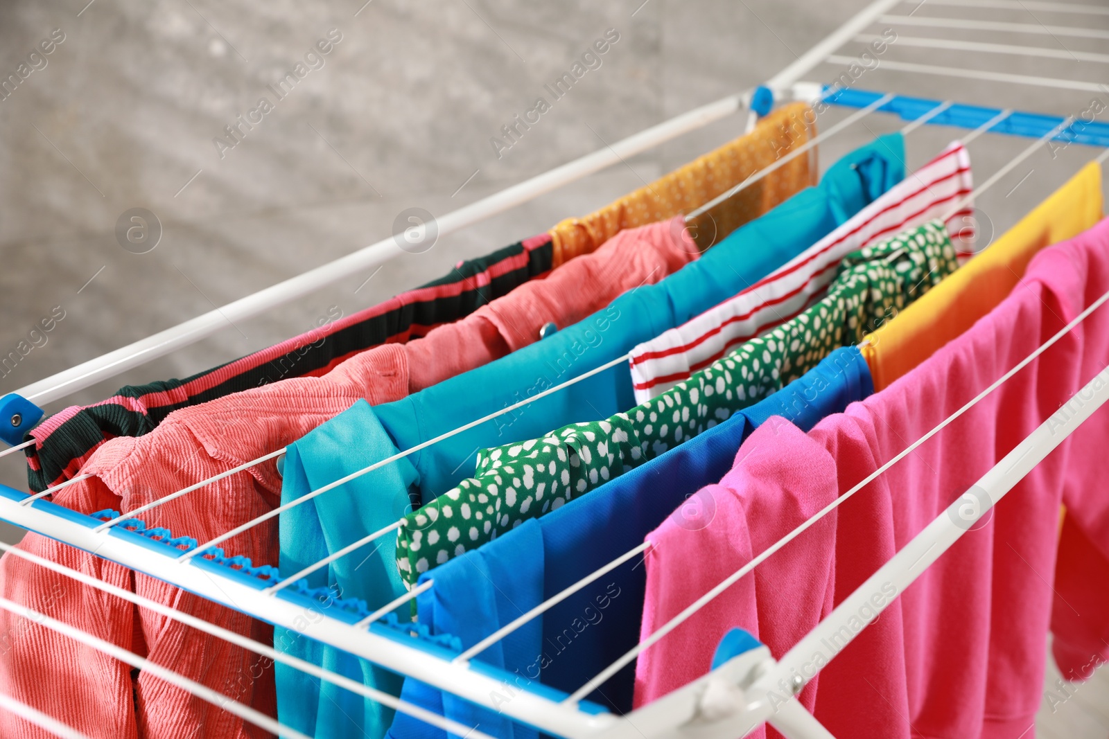 Photo of Clean laundry hanging on drying rack indoors, closeup