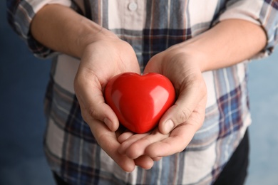 Photo of Woman holding red heart in hands, closeup. Helping and supporting concept