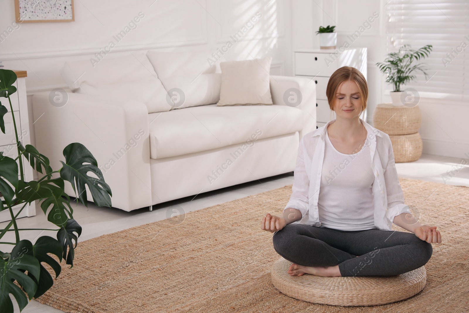 Photo of Woman meditating on wicker mat at home. Space for text