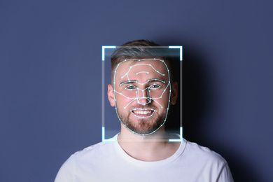 Facial recognition system. Young man with scanner frame and digital biometric grid on dark background