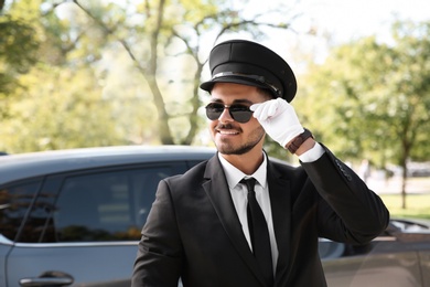 Photo of Young handsome driver standing near luxury car. Chauffeur service