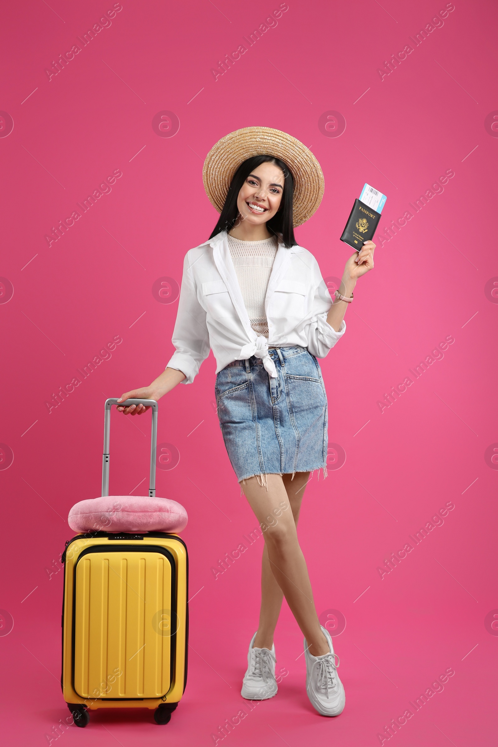 Photo of Happy female tourist with suitcase, ticket and passport on pink background