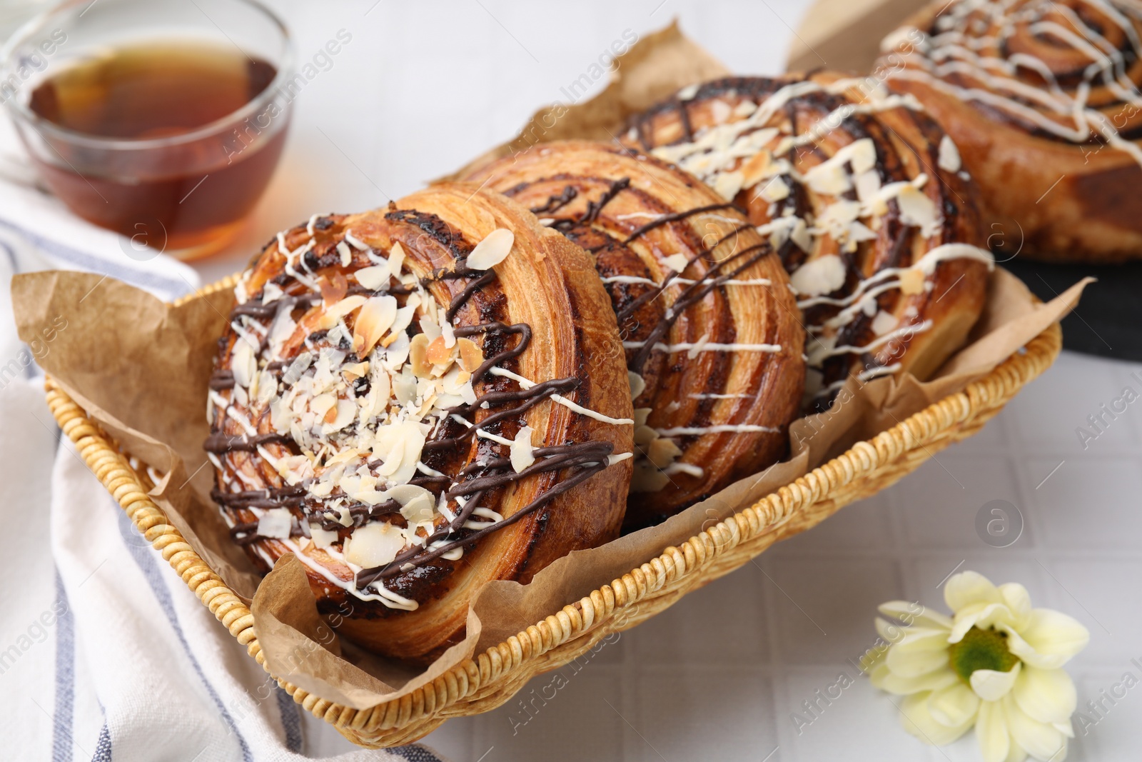 Photo of Delicious rolls with toppings and almond on white tiled table, closeup. Sweet buns