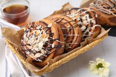 Photo of Delicious rolls with toppings and almond on white tiled table, closeup. Sweet buns