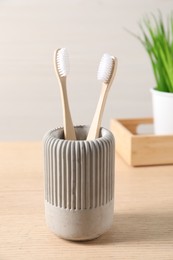 Photo of Bamboo toothbrushes in holder on wooden table