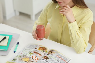 Photo of Woman with delicious smoothie at table indoors, closeup