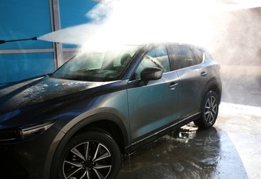 Photo of Cleaning automobile with high pressure water jet at car wash