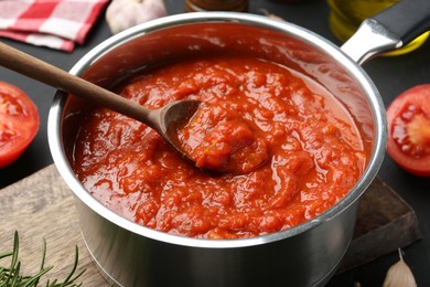 Photo of Homemade tomato sauce and spoon in pot on table, closeup