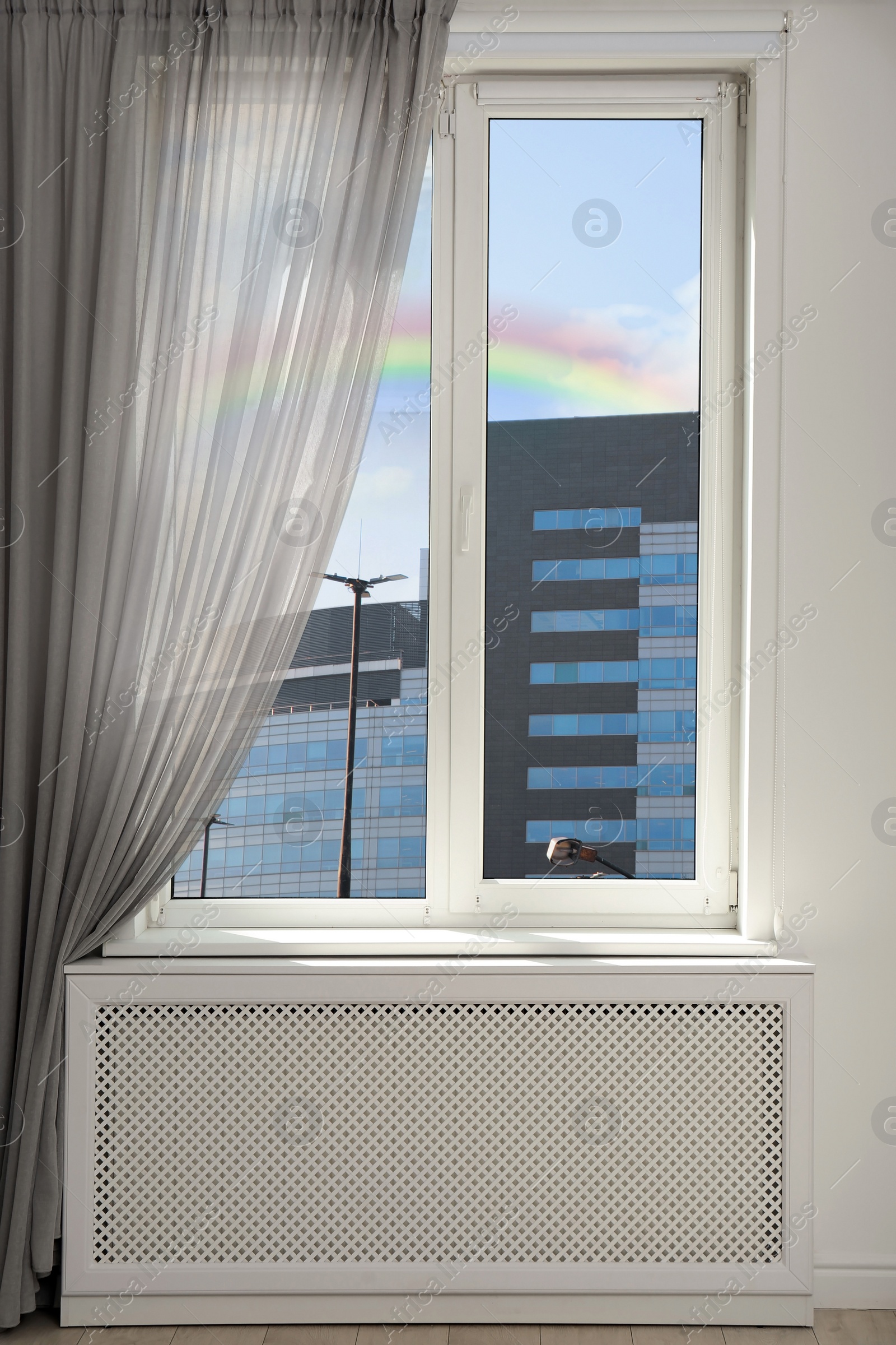 Image of View of beautiful rainbow in blue sky through window