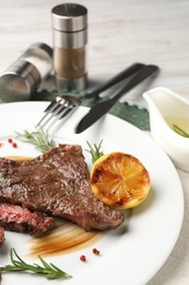 Delicious grilled beef steak with spices and lemon served on table, closeup
