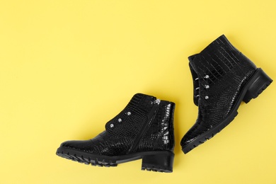 Photo of Pair of stylish ankle boots on yellow background, top view