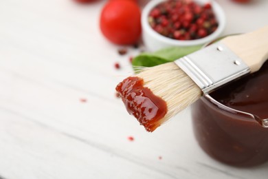 Photo of Marinade and basting brush on white table, closeup. Space for text