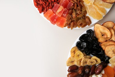 Plates with different dried fruits on white background, top view. Space for text