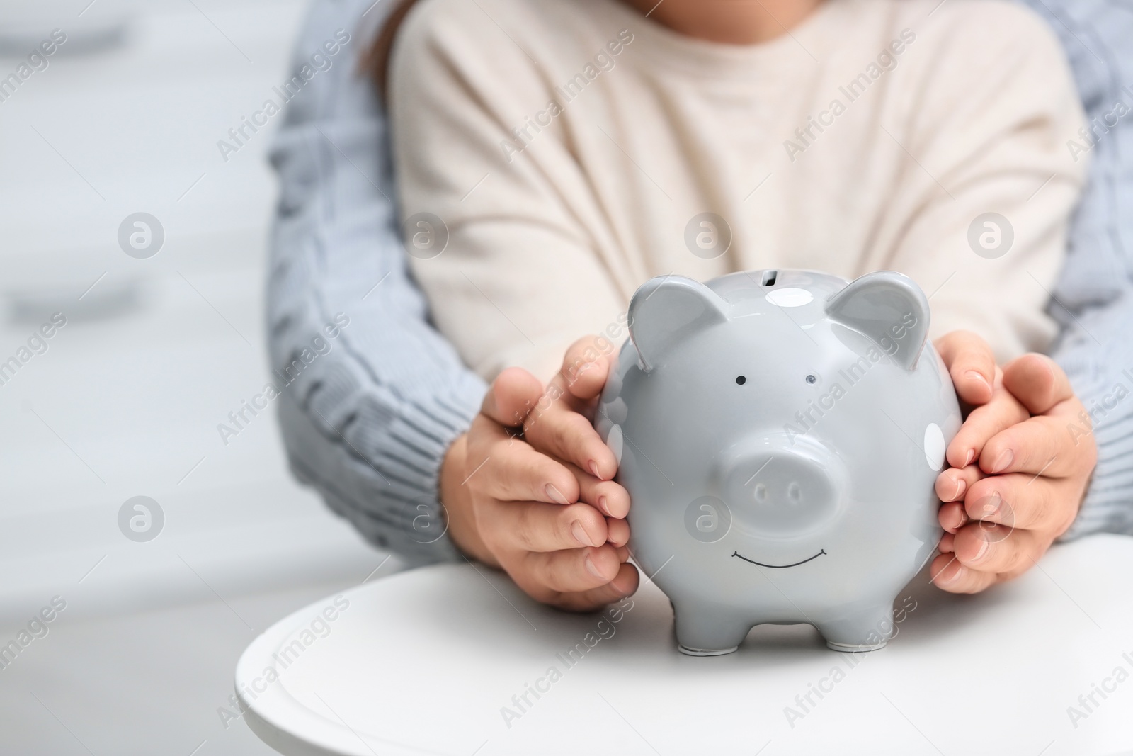 Photo of Couple with piggy bank at white table, closeup