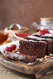 Tasty chocolate sponge cake with nuts and berries on wooden table, closeup