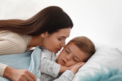 Mother taking care of her little son suffering from cold in bed