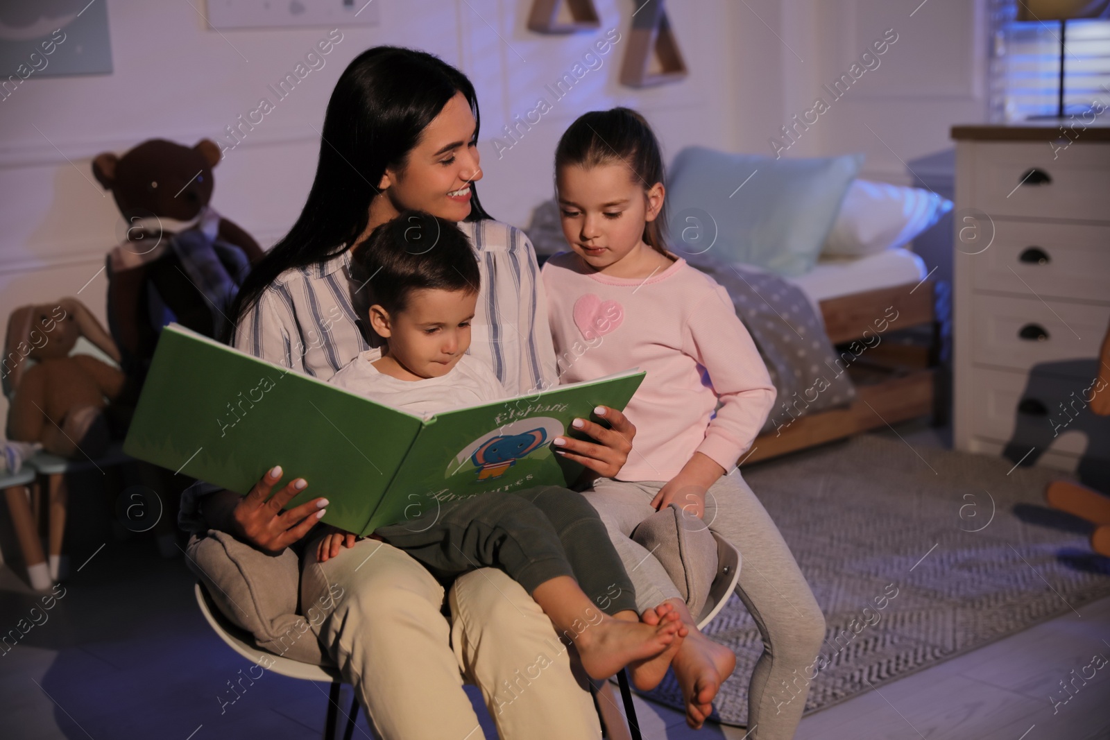 Photo of Mother reading bedtime story to her children at home