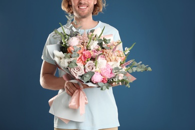 Photo of Man holding beautiful flower bouquet on blue background, closeup view