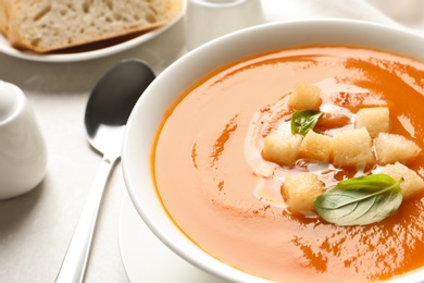 Photo of Bowl of sweet potato soup with croutons and basil served on table, closeup. Space for text